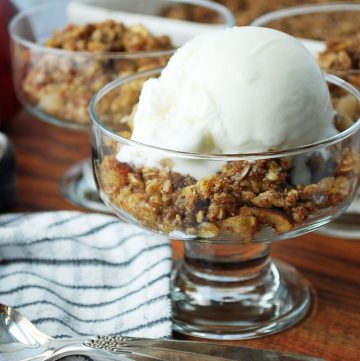close up photo of parfait dish with apple crisp and a scoop of vanilla ice cream