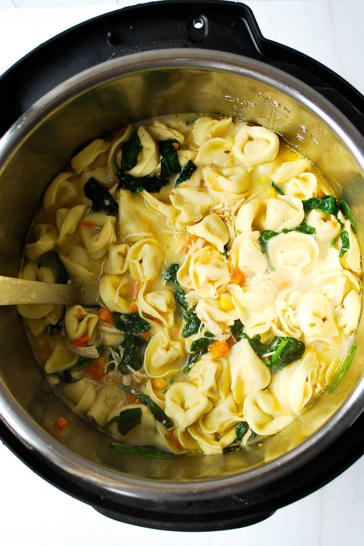 finished creamy tortellini soup with chicken and spinach in an instant pot ready to serve