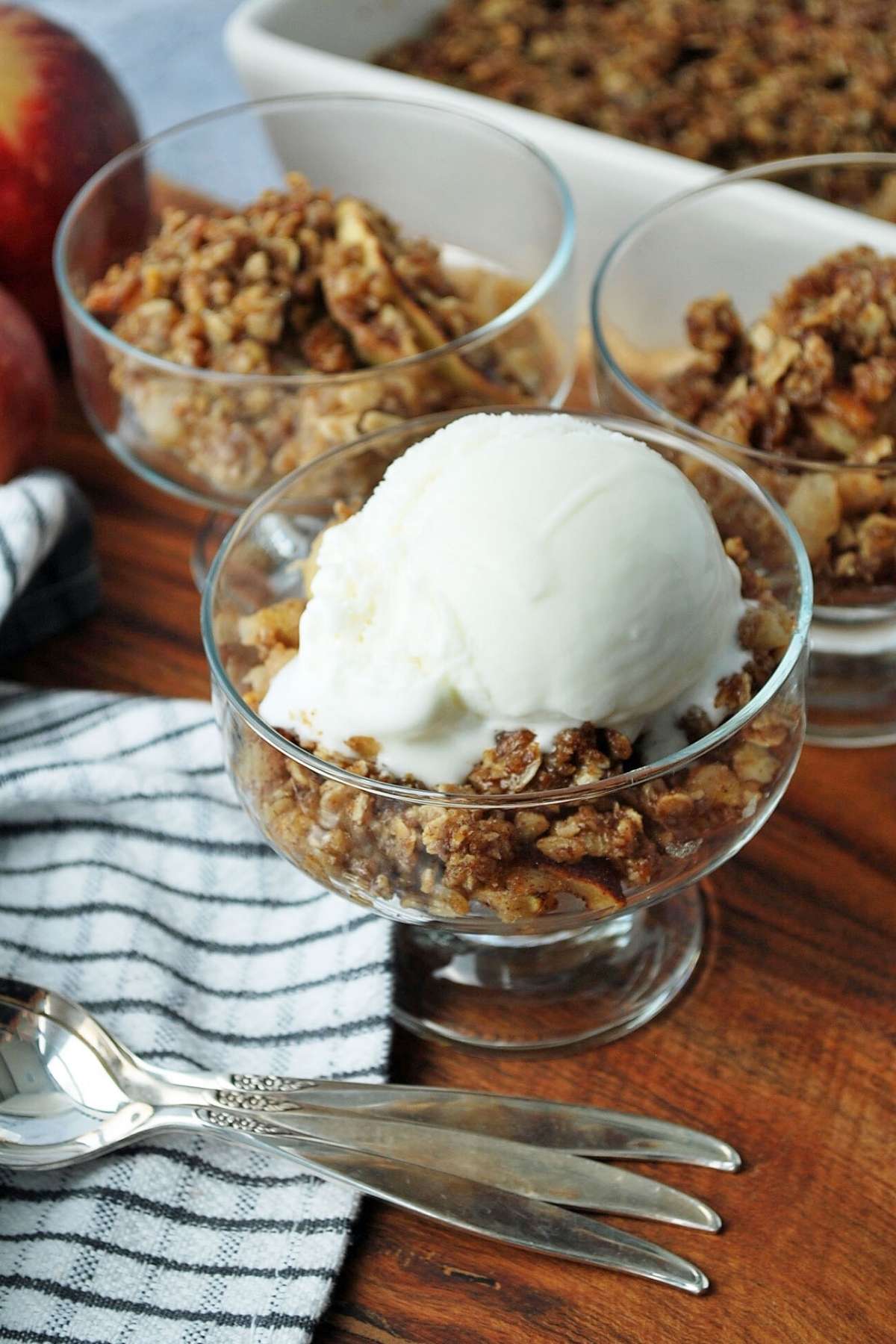 apple crisp in dessert dishes with spoons and a napkin