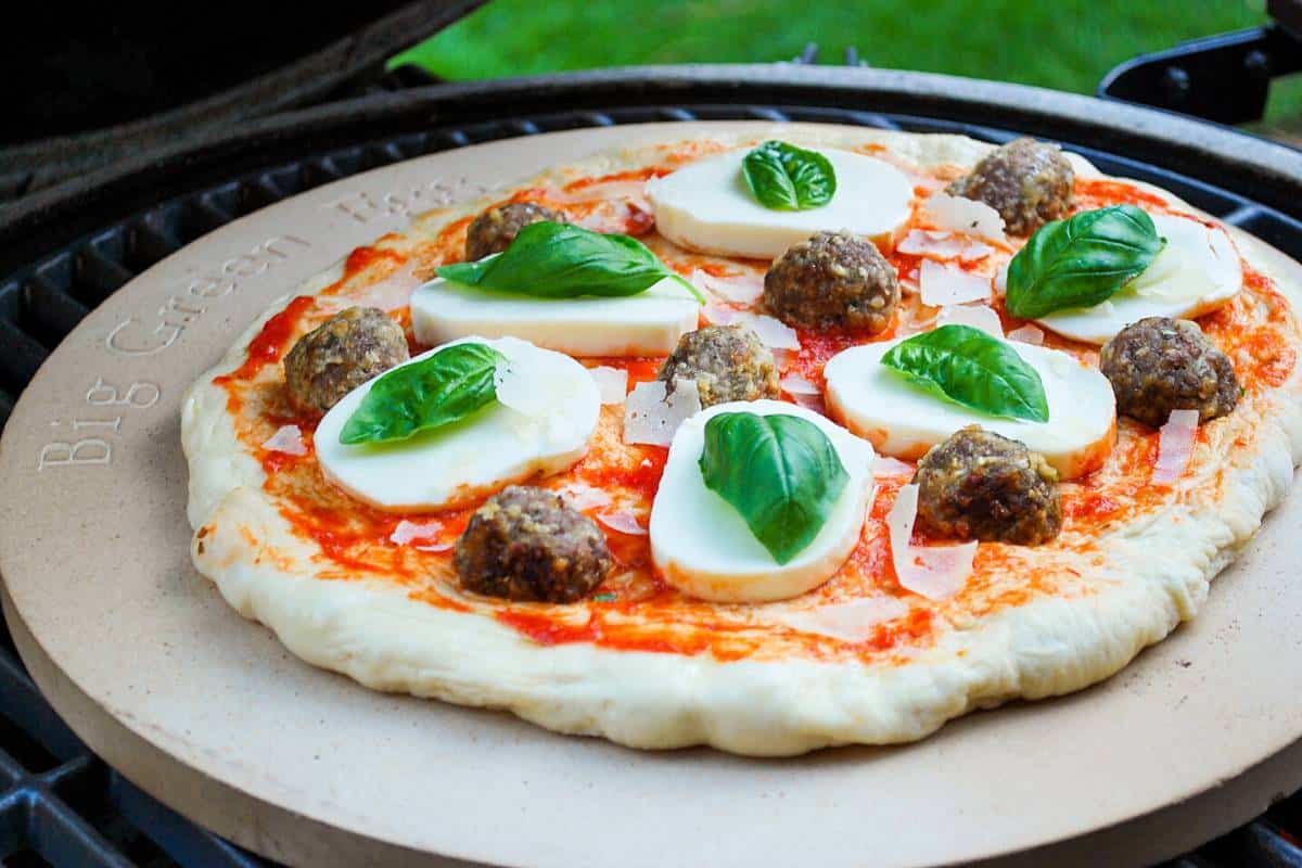 meatball basil and mozzarella pizza cooking on a big green egg