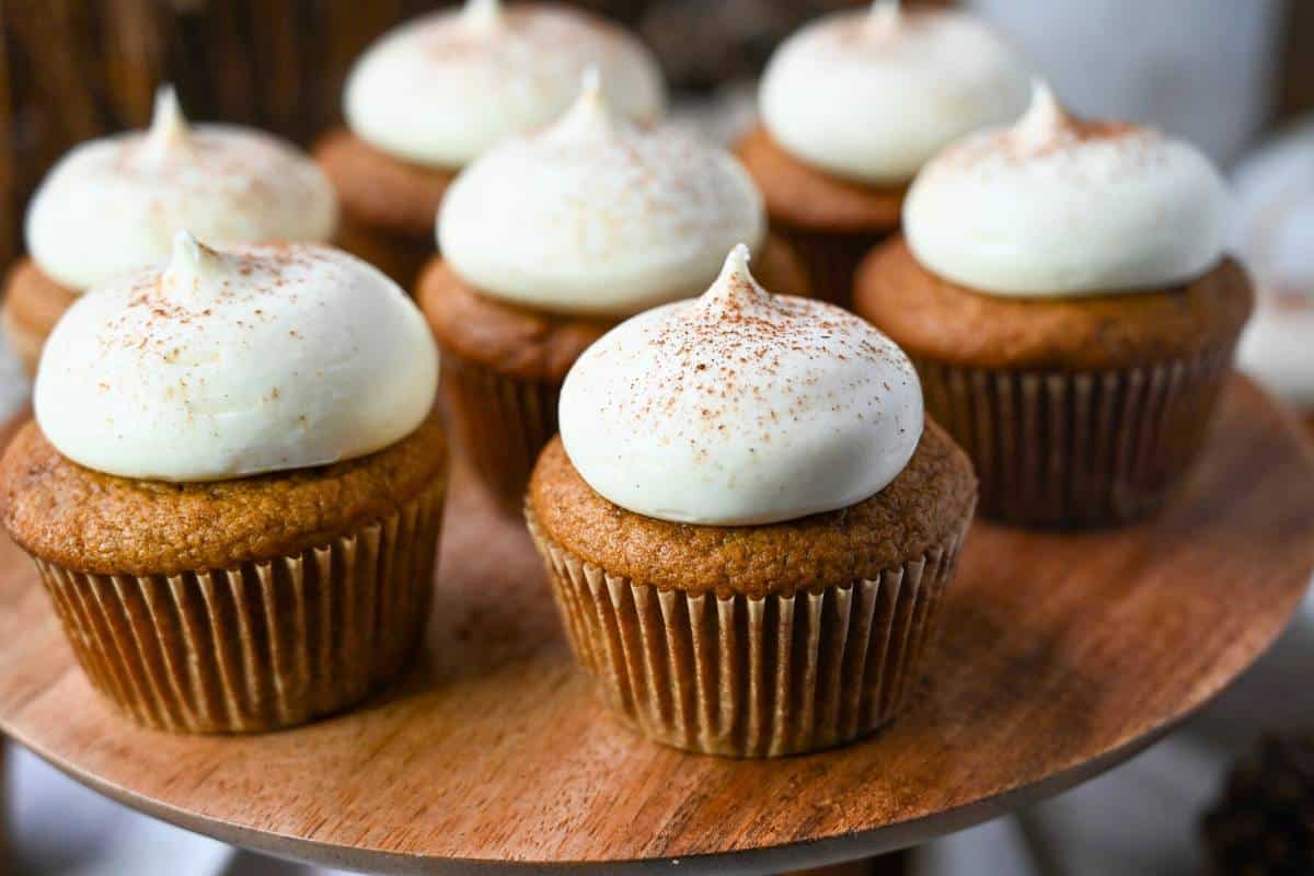 pumpkin spice cupcakes with a swirl of maple frosting on a wooden platter