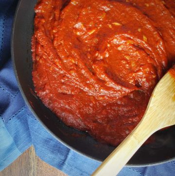 pizza sauce in a skillet with a wooden spoon