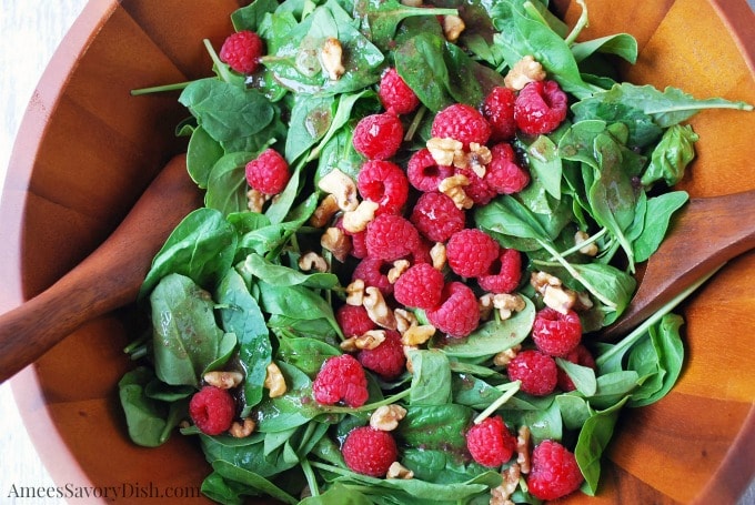 Raspberry spinach salad aka Christmas salad in a wood bowl with salad spoons