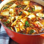 Italian sausage soup serve in a dutch oven with a napkin in background
