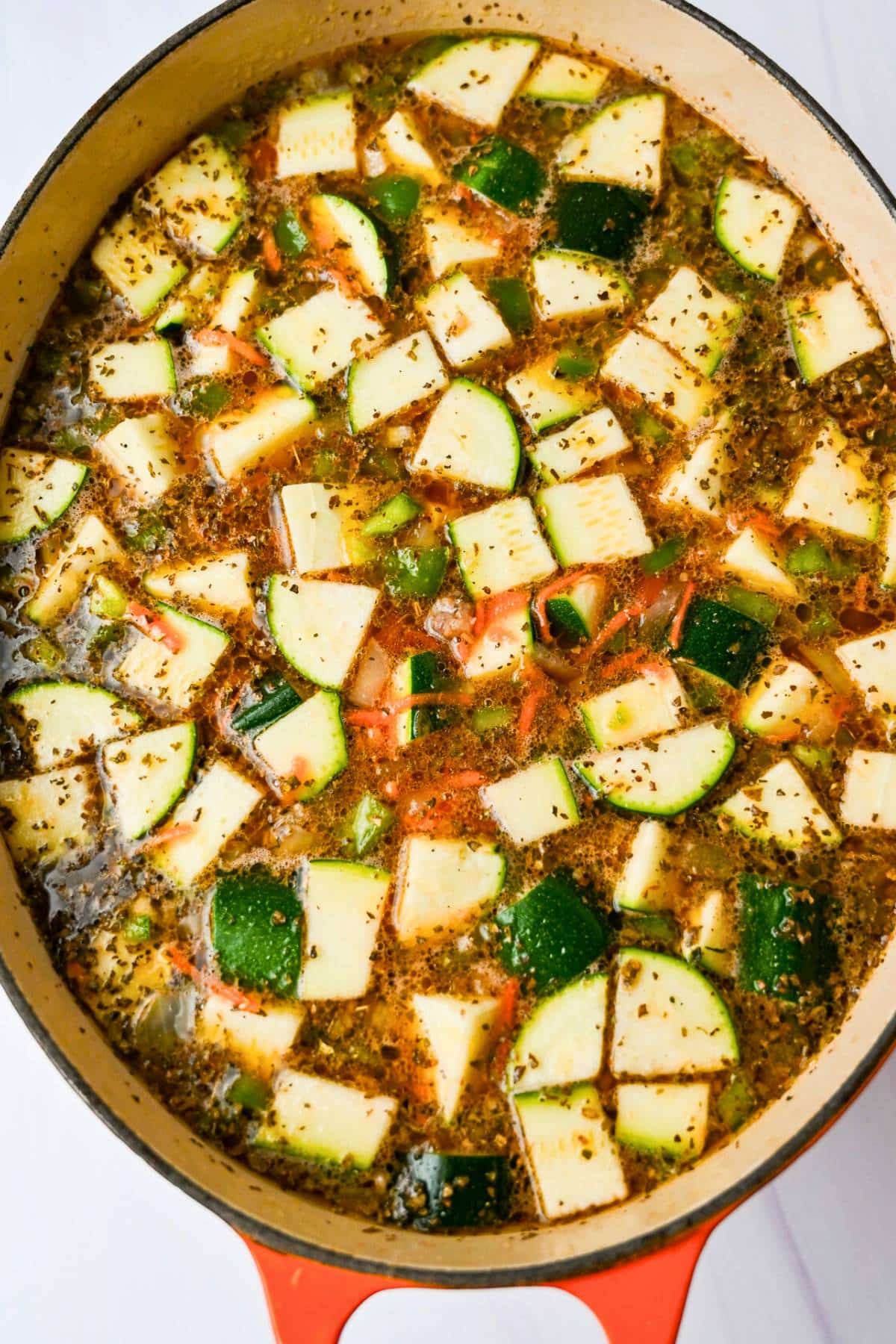 a dutch oven with beef and wine stock with vegetables and sausage