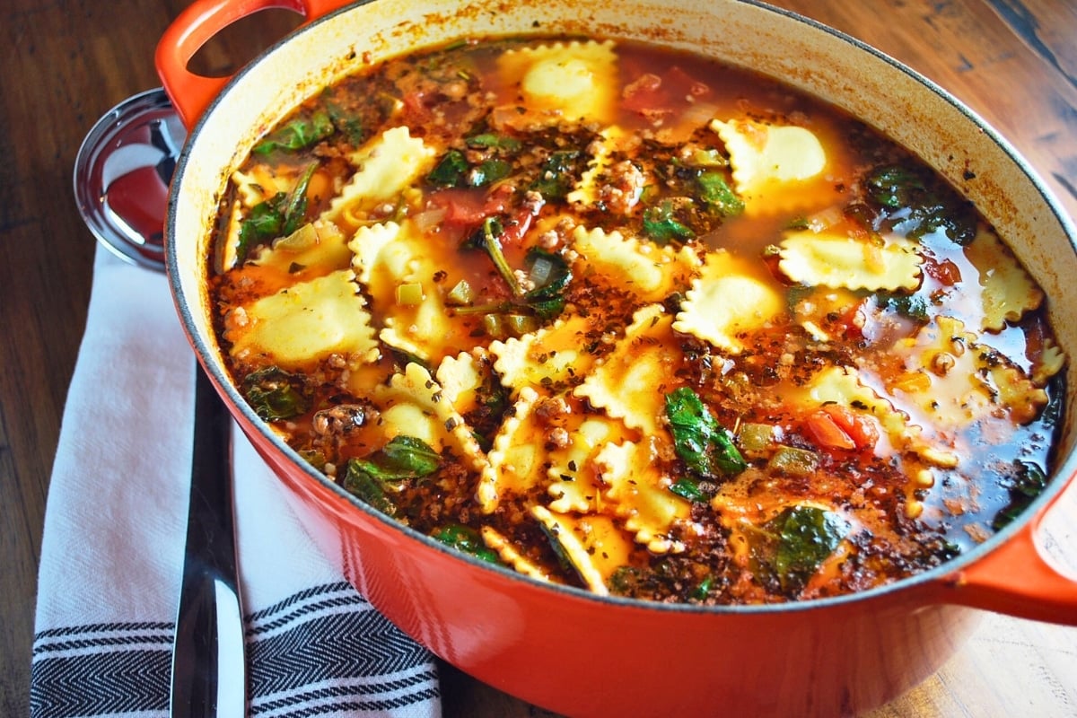 a pot of ravioli soup with a soup ladle and napkin