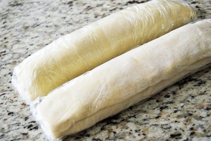Rolled up pinwheel appetizers wrapped in plastic wrap ready to freeze