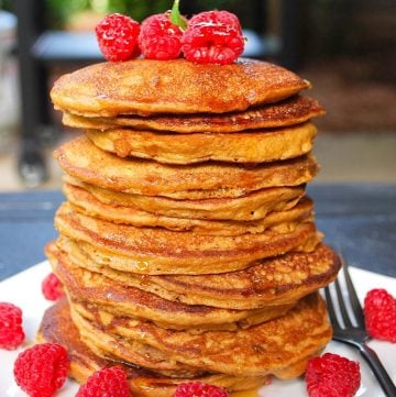 close up photo of a tall stack of Blackstone pancakes with fresh raspberries with a Blackstone griddle in the background
