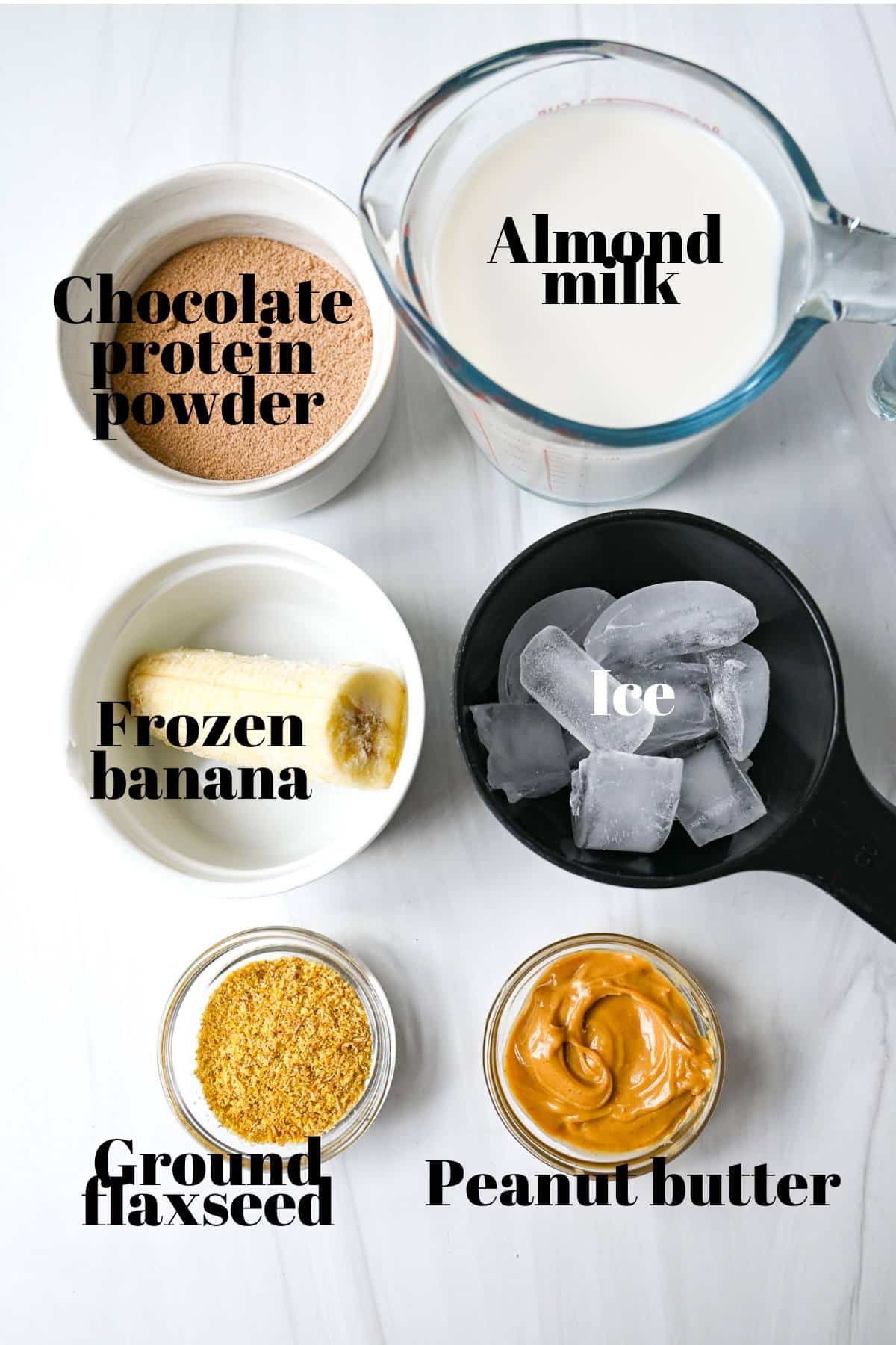 ingredients for making a protein shake with chocolate protein powder, frozen banana, and peanut butter measured out on a counter