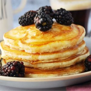 stack of buttermilk pancakes dripping with syrup