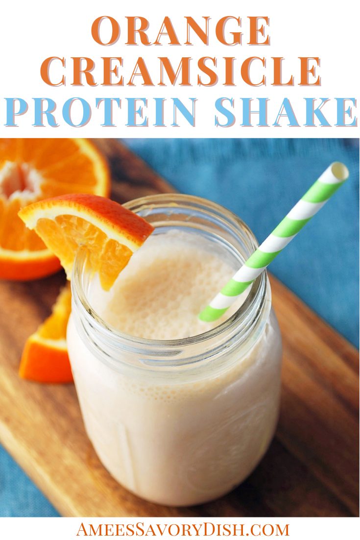orange protein shake in a mason jar with orange slices and a green straw