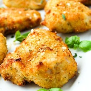 close up photo of air fried parmesan crusted chicken garnished with fresh basil
