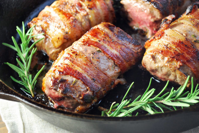 Bacon-wrapped venison loin cooked in a cast iron skillet