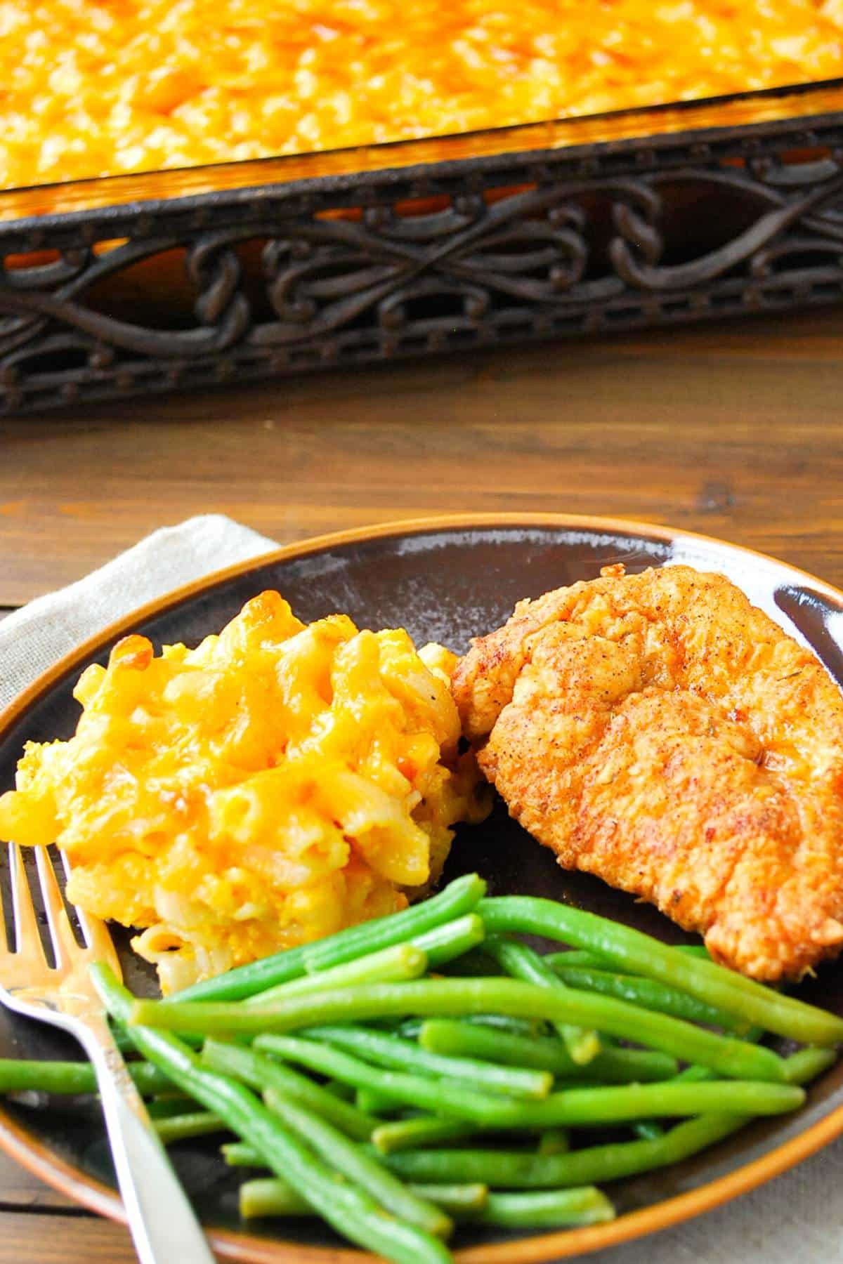 Macaroni and cheese on a plate with chicken and green beans