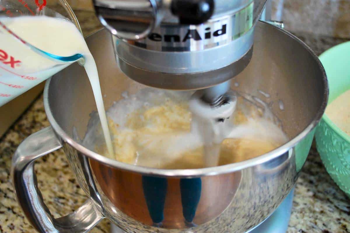 adding milk to bread batter in a mixing bowl