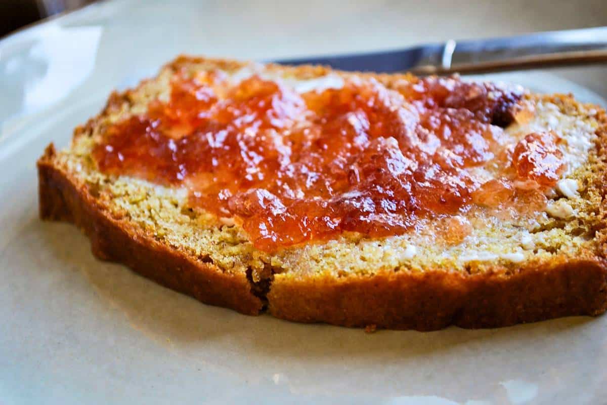 a slice of bread with strawberry jam and a knife