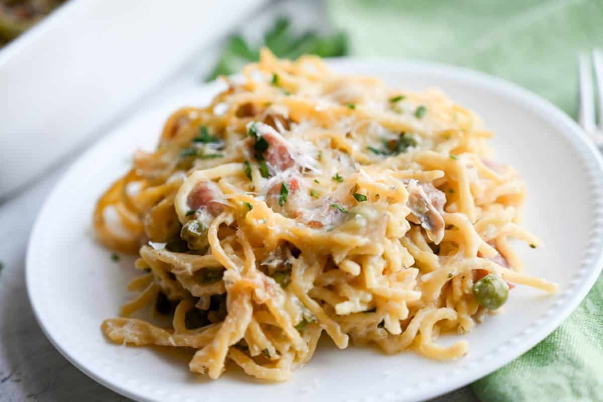 spaghetti casserole sprinkled with fresh parm on a plate with parsley around it