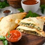a sliced spinach and cheese calzone with sauce