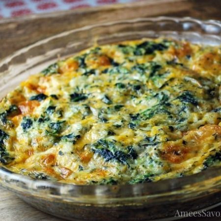Spinach quiche in a glass pie plate on a wooden tray