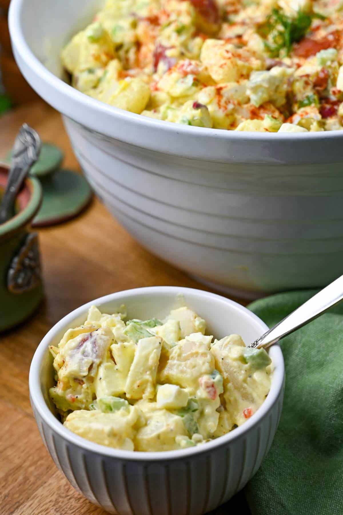 a small serving dish of red potato salad with a bowl of potato salad behind it