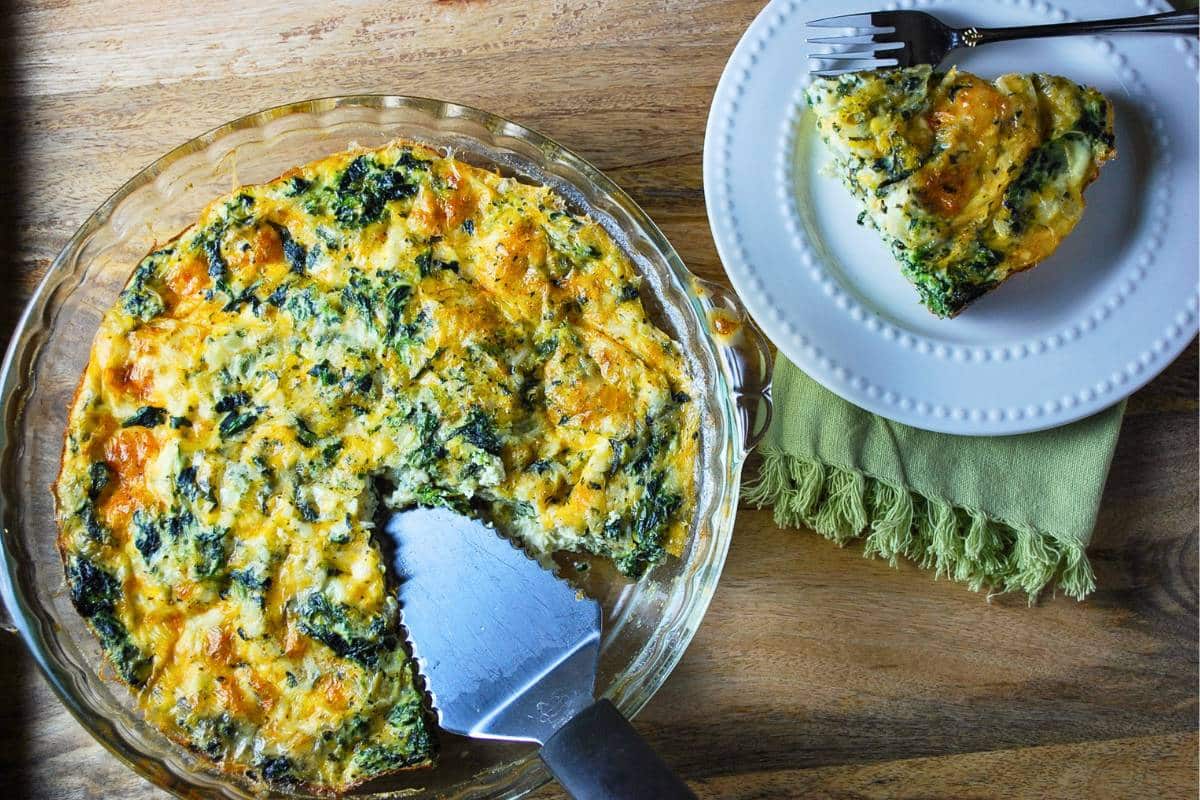 a sliced crustless cottage cheese quiche with a spatula and a served piece of quiche on a plate