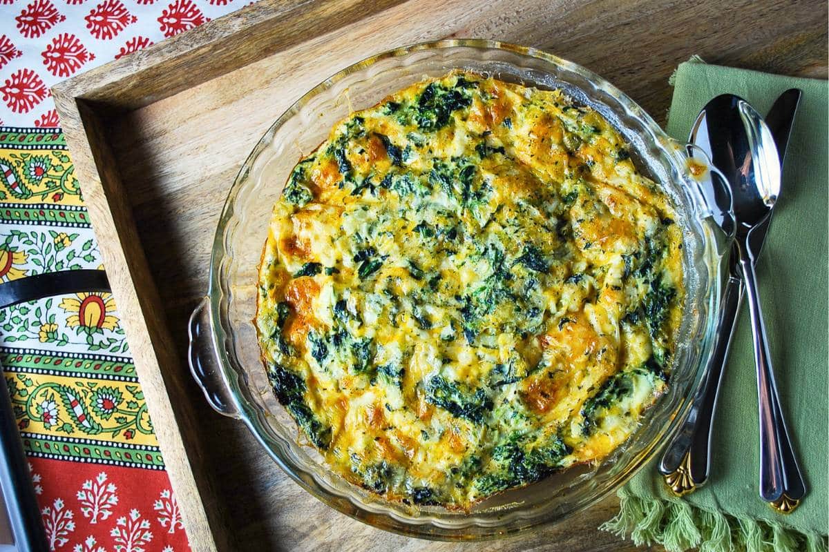 a quiche with a knife, spoon, and napkin