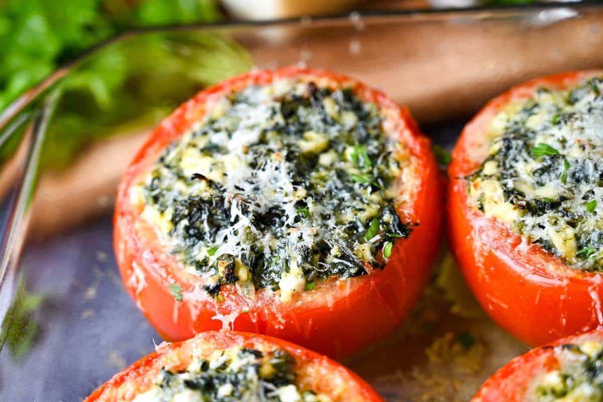 zoomed in photo of a baked tomato with a bubbly spinach and cheese filling