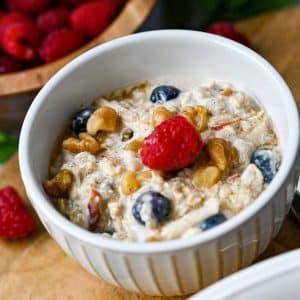 a small bowl of bircher muesli with blueberries and a raspberry on top