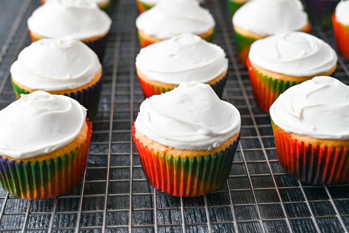frosted vanilla cupcakes on a cooling rack