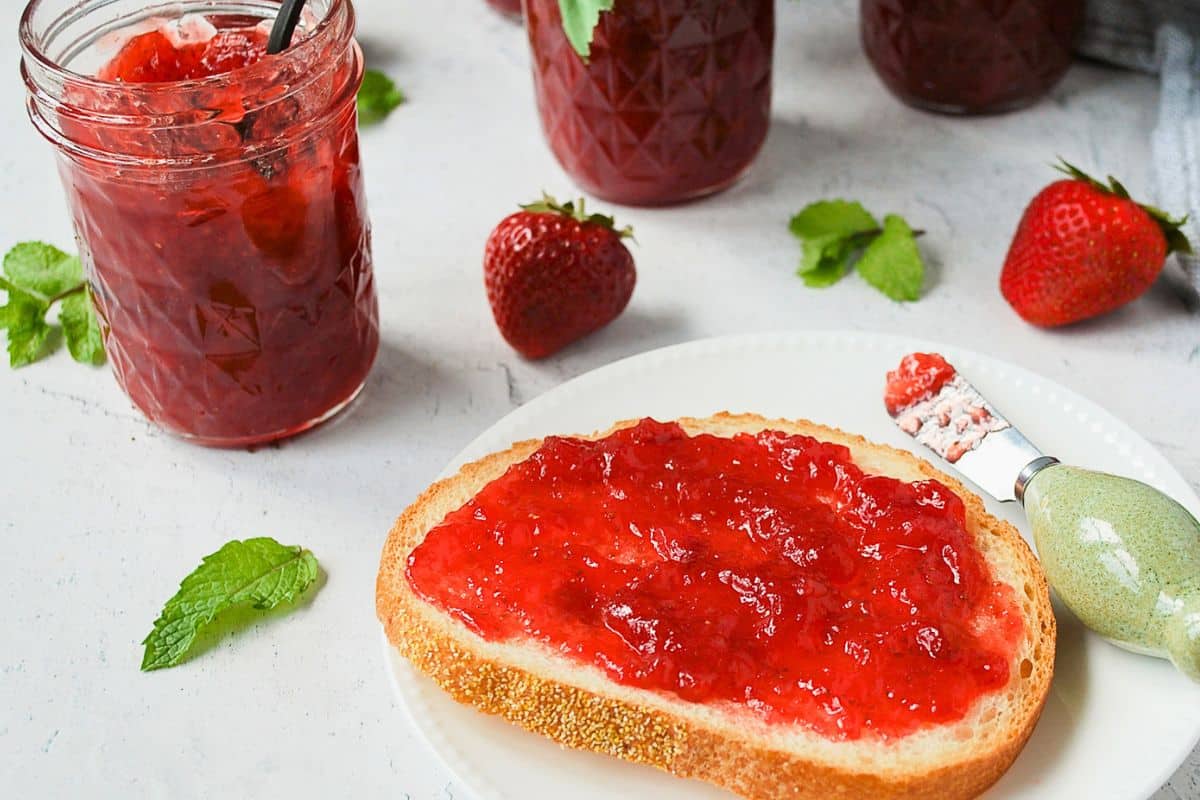jam on toast with jars of jam in the background