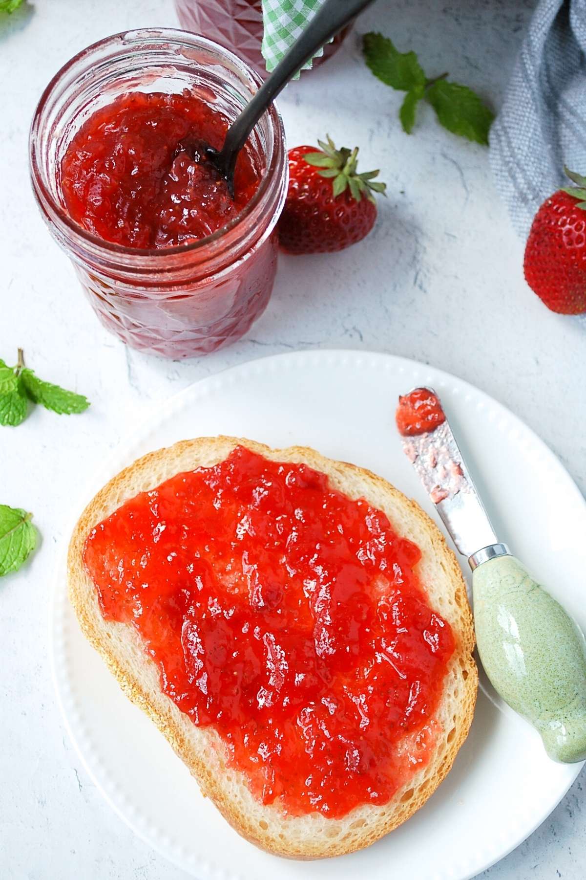 strawberry jam on toast with an open jar of jam with a spoon