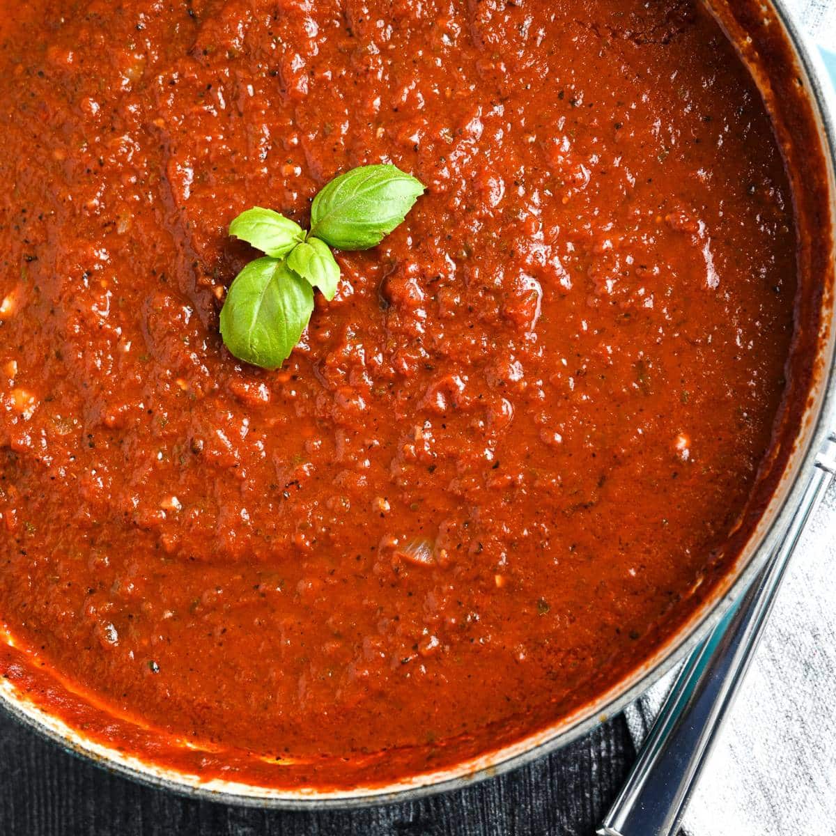 overhead photo of a pan of marinara sauce topped with basil