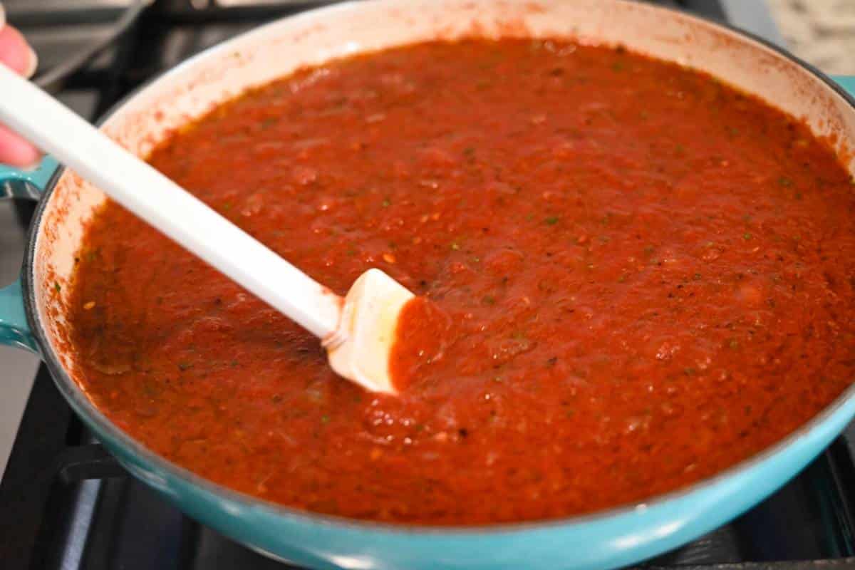 marinara simmering on the stove with a spatula stirring