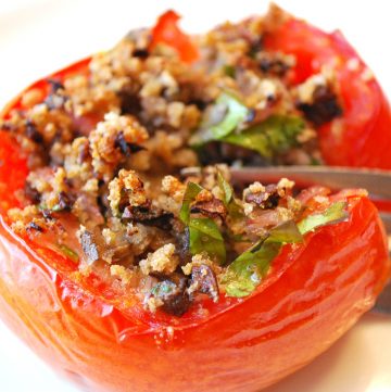 close up of a stuffed tomato with a fork slicing down the center