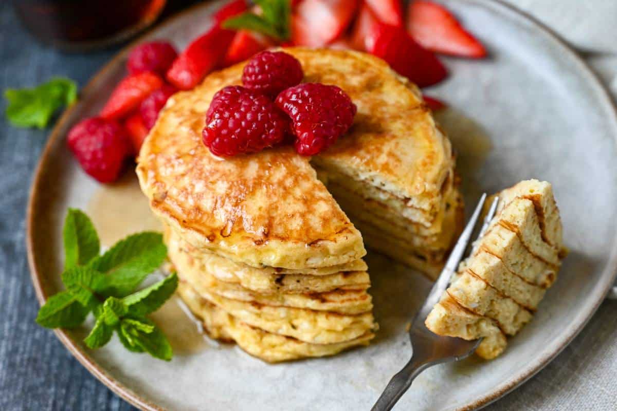 a plate of protein cottage cheese pancakes with a sprig of mint and berries