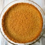 a baked graham cracker pie crust in a clear pie dish