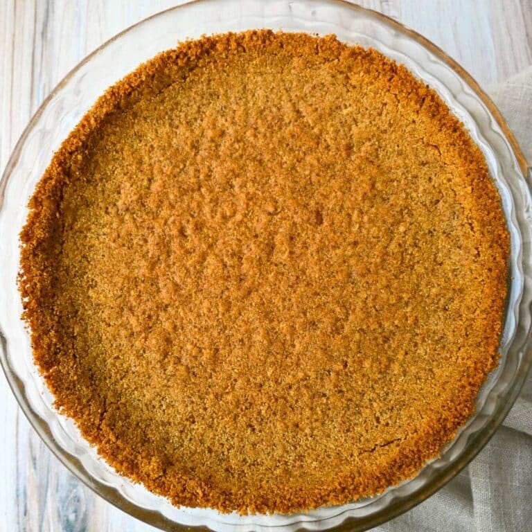 a baked graham cracker pie crust in a clear pie dish