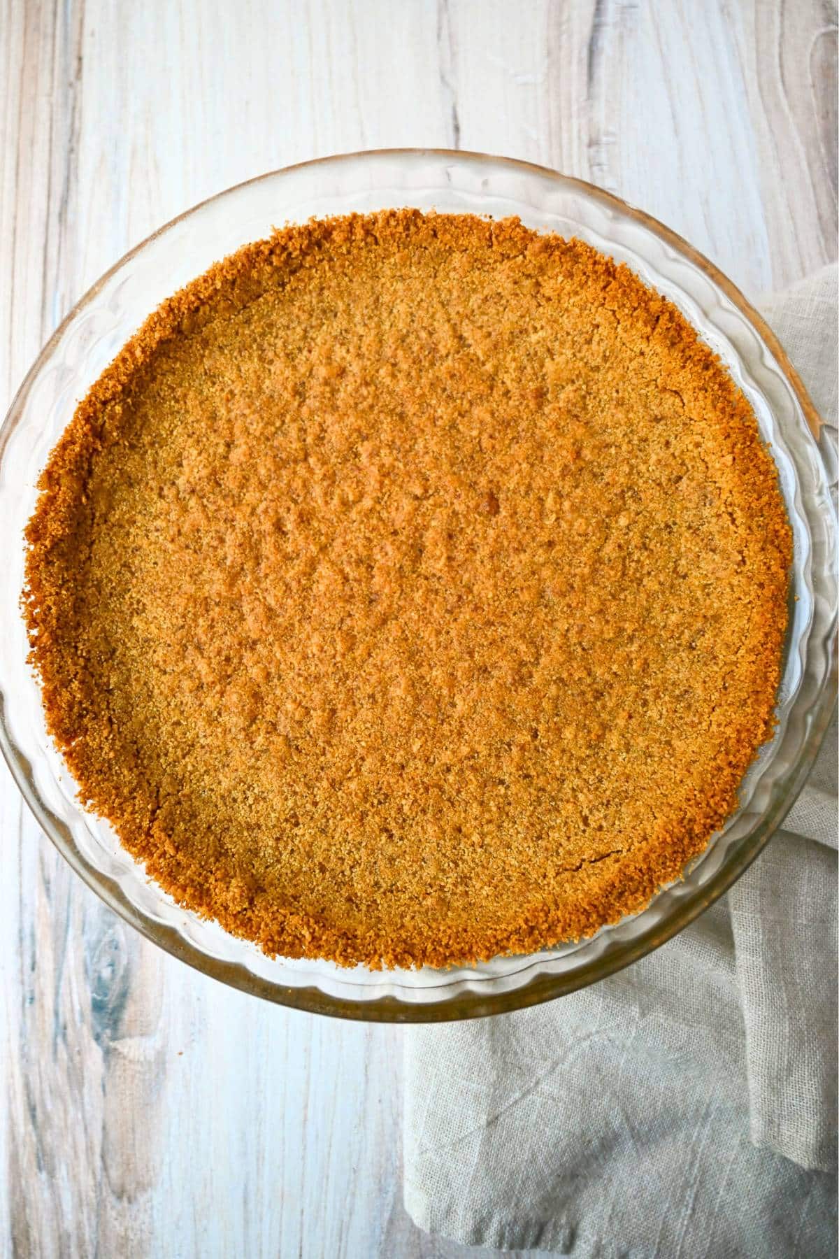 a baked graham cracker pie crust on a counter with a napkin