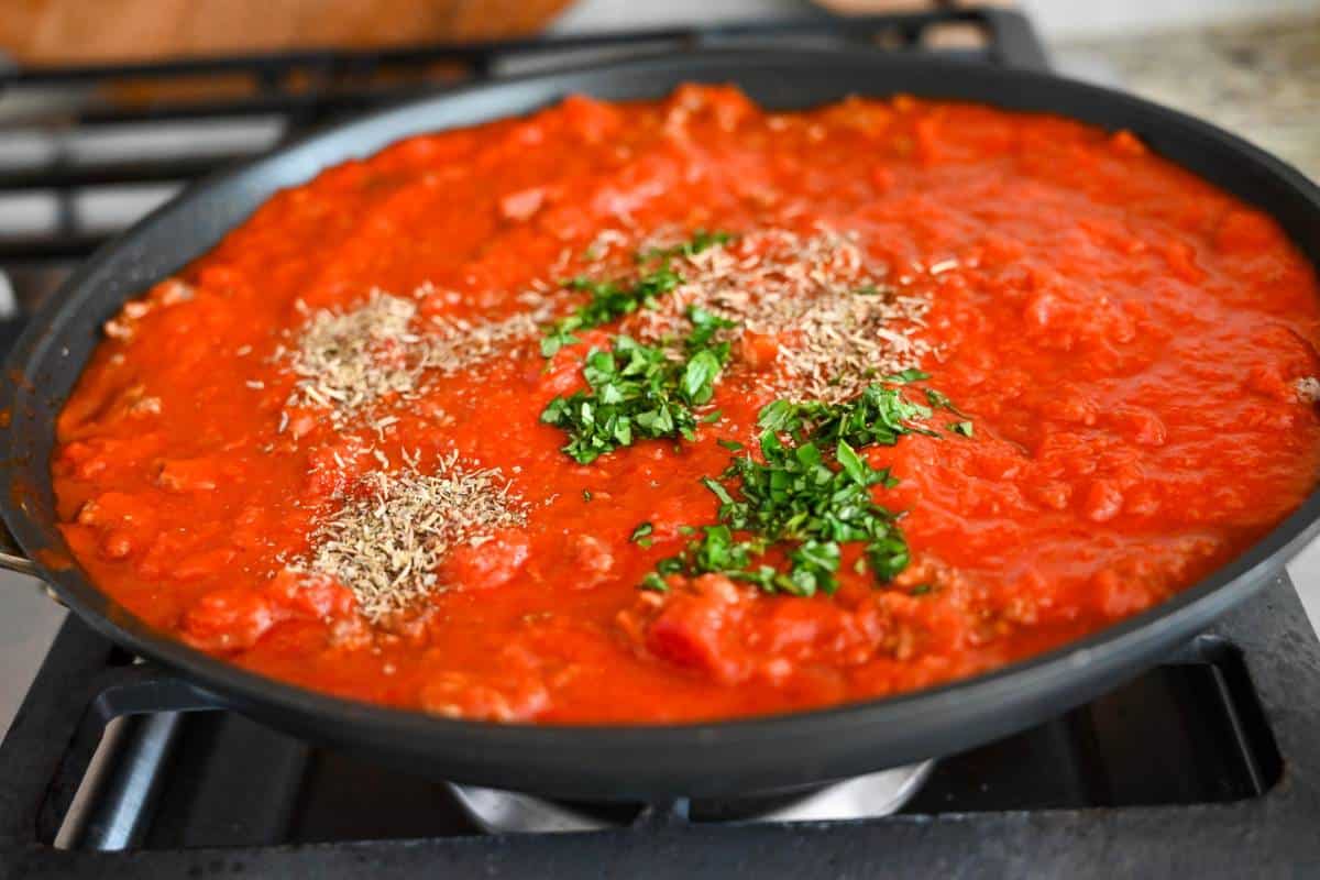 marinara sauce with ground beef cooking on a stovetop