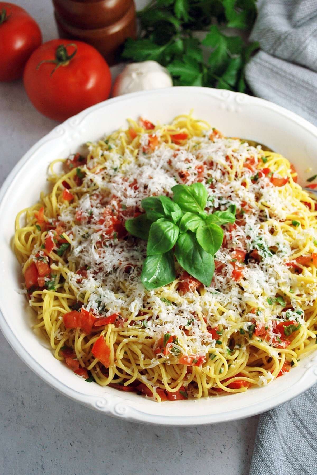 large bowl of pasta tossed with fresh tomato basil sauce and garnished with basil and cheese
