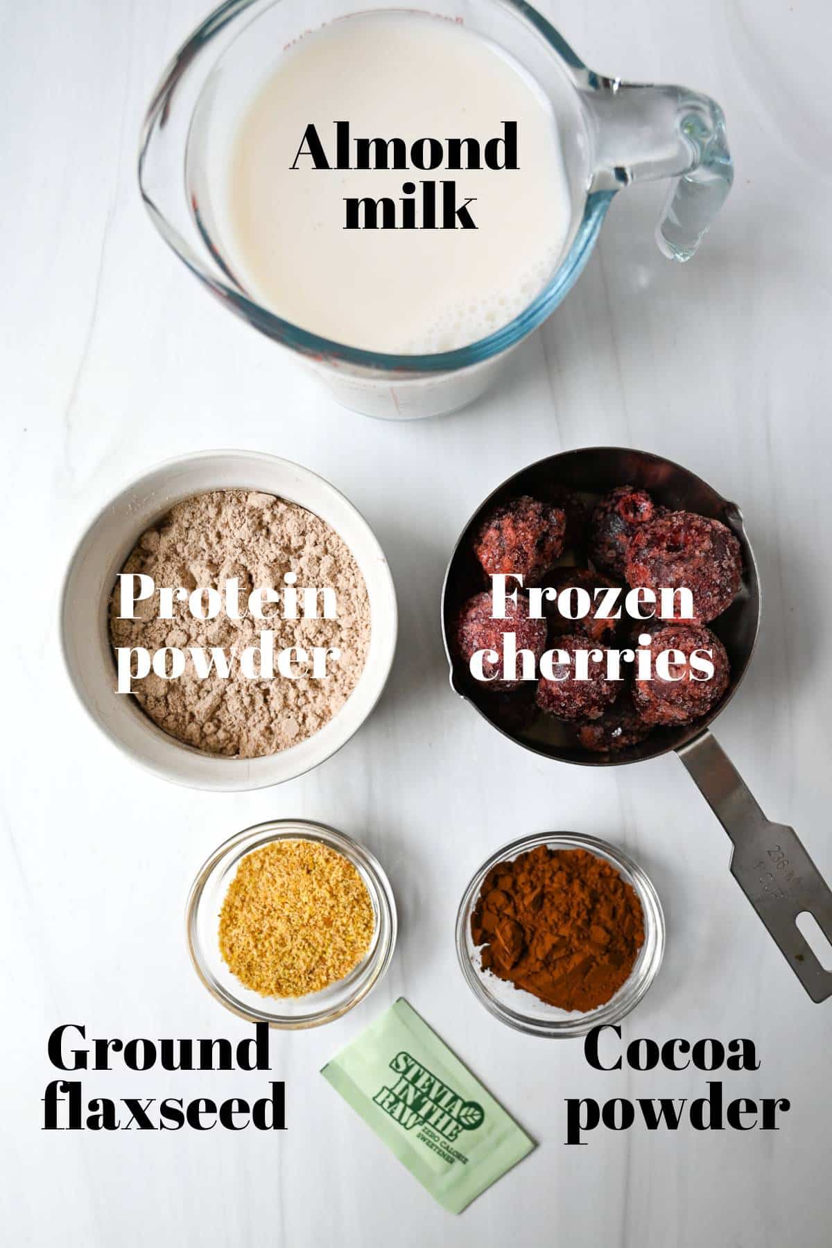 ingredients for making a cherry chocolate protein shake in a blender on a counter