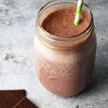 chocolate cherry protein shake in a mason jar with green striped straw