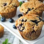 close up of three muffins with fresh blueberries on a platter
