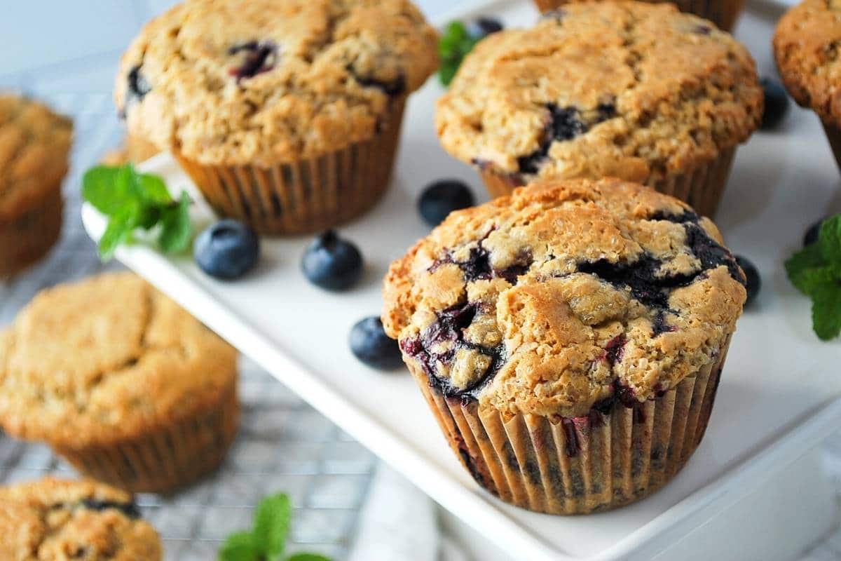 fresh blueberry muffins with berries sprinkled around them 
