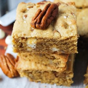 close up of a stack of gluten free blondies topped with coarse salt and a pecan