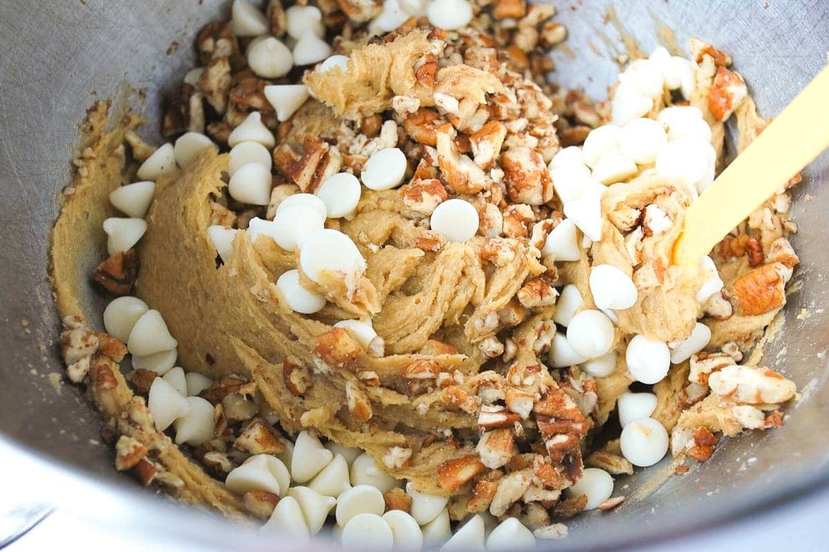 stirring white chocolate chips and pecans into gluten free blondie batter