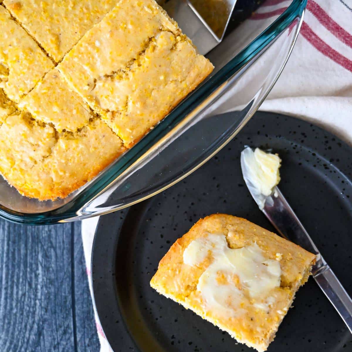 buttered slice of cornbread with a pan of cornbread behind it