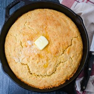 cornbread baked in an iron skillet with a pat of butter on top