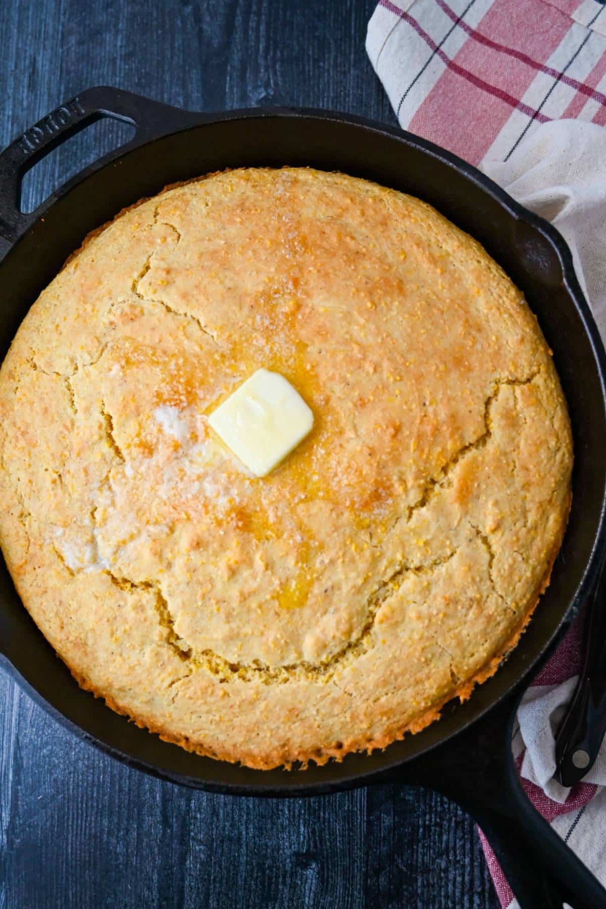 gluten free cornbread in a cast iron skillet with a pat of butter on top