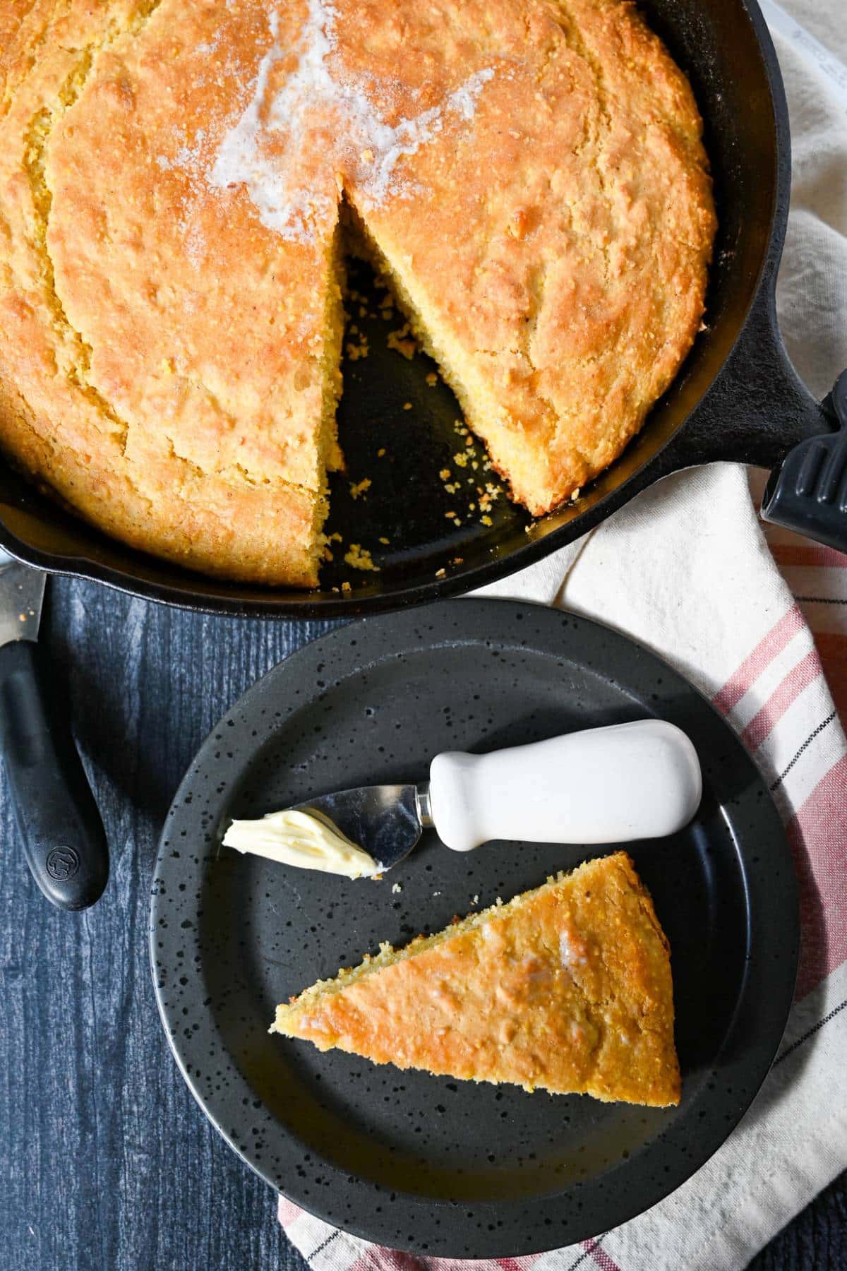 gluten-free cornbread in a cast iron skillet with a slice cut out on a plate
